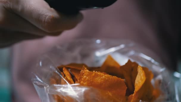 Paquete femenino de papas fritas presiona botones con los dedos en el control remoto de TV - Metraje, vídeo