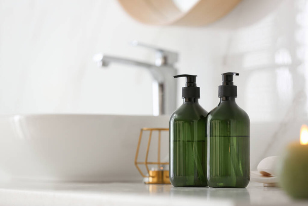 Green soap dispensers on countertop near sink in bathroom. Space for text - Φωτογραφία, εικόνα