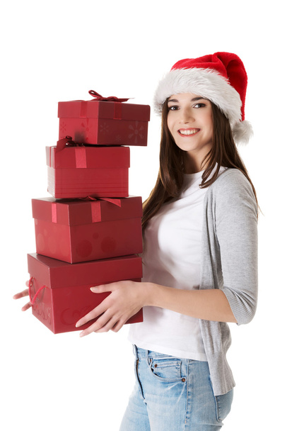 Woman in santa hat, holding stock of presents. - 写真・画像