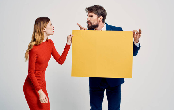 Energetische vrouw neemt de mockup poster uit de handen van een man reclame model - Foto, afbeelding