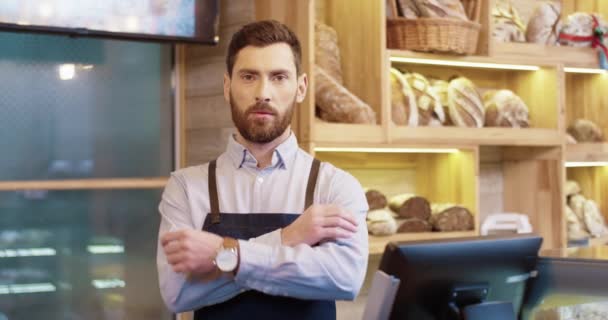 Зворотний портрет Кавказького радісного бородатого вродливого пекаря, що стоїть у маленькій пекарні в доброму настрої, дивиться на камеру і посміхається поодинці. Власник Бейкгаузу. Концепція бізнесу - Кадри, відео