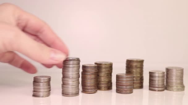 Die Hand einer Frau legt Münzen in eine Säule. Investitionskonzept. Metallische Währung. - Filmmaterial, Video