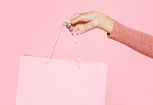 Abrir loja e descontos para os clientes. Mão da jovem senhora afro-americana segurando saco de compras rosa - Foto, Imagem