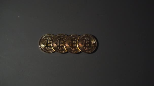 čtyři bitcoinové mince na černém pozadí, mužské ruce je sbírají jeden po druhém. Koncept nákupu a prodeje kryptoměn. - Záběry, video