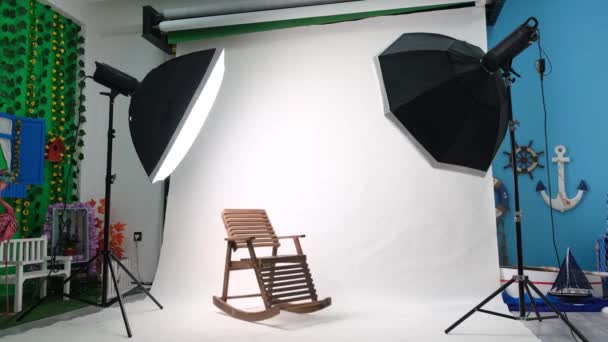 Στούντιο φωτογραφίας ή βίντεο με δύο εξαγωνικά φώτα στούντιο. Λευκή οθόνη και κουνιστή καρέκλα - Πλάνα, βίντεο
