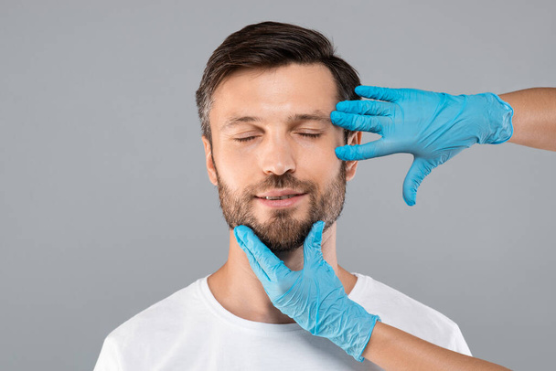 Középkorú, szakállas férfi csukott szemmel, aki kozmetikai injekciót kap. - Fotó, kép