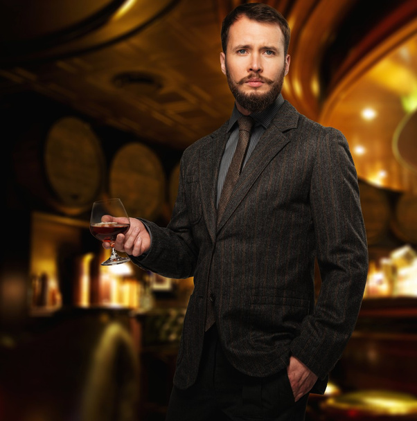 knappe goed-geklede man in jas met glas van de drank in restaurant interieur  - Foto, afbeelding