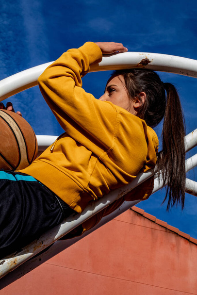 joueur de basket dans un haut rose assis sur un terrain de basket urbain - Photo, image