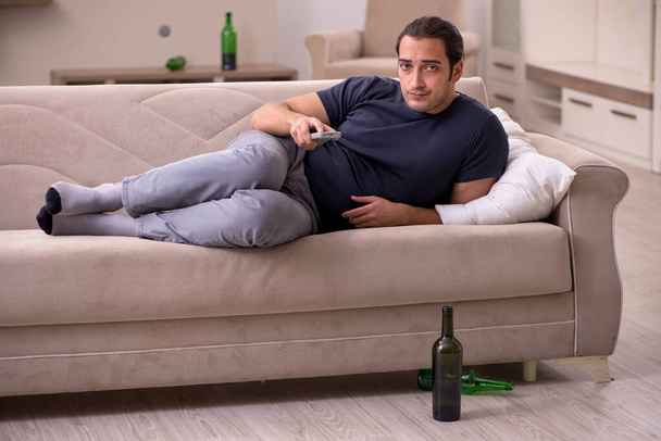 Joven alcohólico masculino viendo la televisión en casa - Foto, imagen