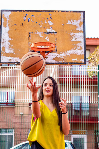 basketball player in a pink top sitting on an urban basketball court - 写真・画像
