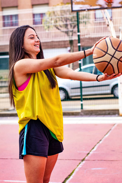 basketball player in a pink top sitting on an urban basketball court - Photo, Image