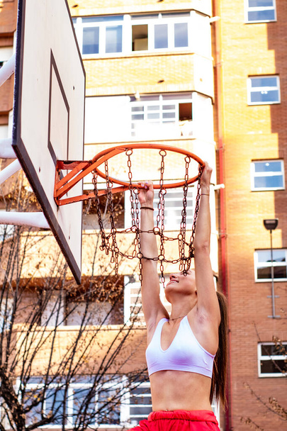 A blonde girl basketball player grabs the basketball hoop - Foto, imagen