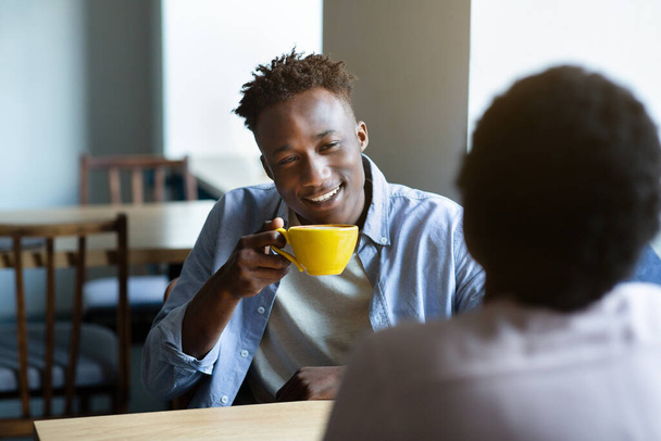 Adorable black couple chatting in coffee shop at lunchtime, having first date, starting romantic relationship - Photo, Image