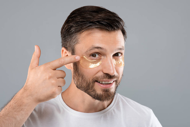 Bonito homem aplicando manchas nos olhos em seu rosto - Foto, Imagem