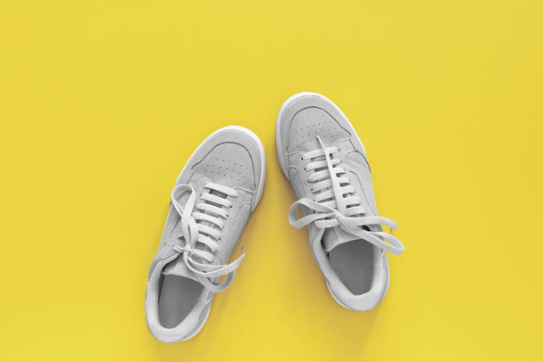 Gray nubuck sneakers isolated on a yellow background, seasonal shoes for walking and sports, top view, trendy colors of the year - 写真・画像