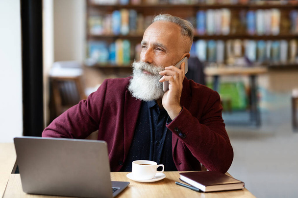 Rušný starší podnikatel mluví po telefonu v kavárně - Fotografie, Obrázek