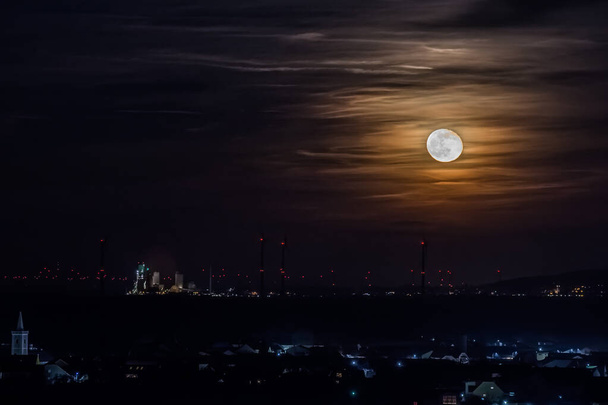 beautiful moon with clouds on the sky and a illuminated city in the night - Photo, Image