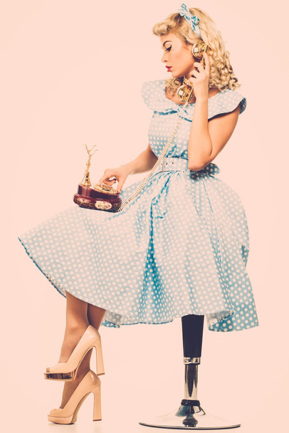 Coquette blonde pin up style jeune femme en robe bleue avec téléphone vintage
  - Photo, image