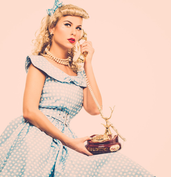 kokette blonde Pin-up-Stil junge Frau in blauem Kleid mit Vintage-Handy  - Foto, Bild