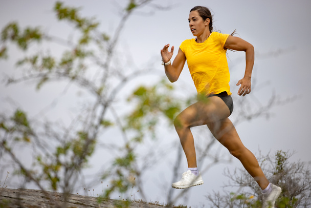Confident donna Sprinting su montagna contro cielo - Foto, immagini