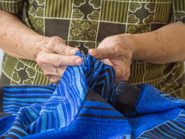 Close-up of senior woman hands using a razor to mend a cloth. - Foto, Imagem