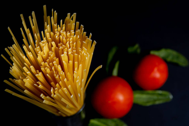 Spaghetti paste, tomato and other products for cooking on dark background top view. Space for text, top view. - Foto, Imagen