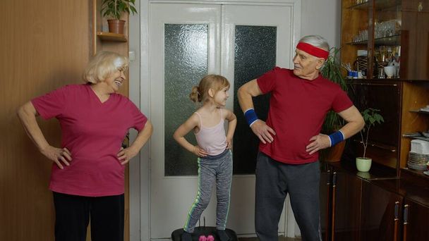 Torunum ve büyükbabam spor kıyafetleriyle evde spor koşusu egzersizleri yapıyor. - Fotoğraf, Görsel