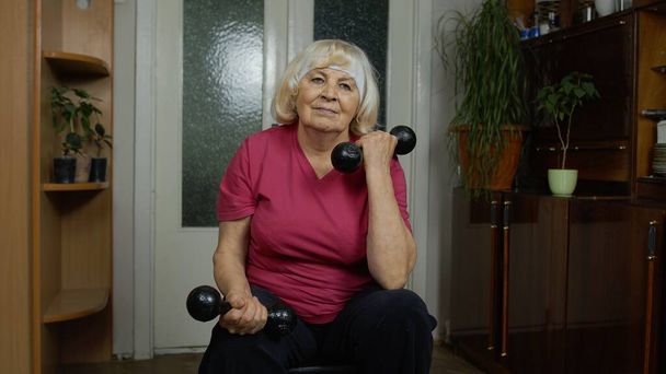 anziano maturo nonna donna facendo sollevamento pesi allenamento manubri esercizio a casa - Foto, immagini