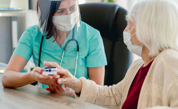 Elderly woman at doctor during coronavirus pandemic - 写真・画像