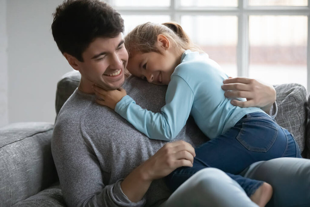 Gros plan heureux père et petite fille câlins sur le canapé - Photo, image