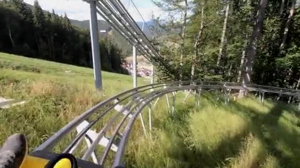 Rodelbahn 'da ya da Alp Coaster' da kayan insanlar sonbahar güneşli günlerinde ağaçların arasında ağaçlarda kızakla kayıyorlar. Tatil turizmi tatili kavramı. POV - Video, Çekim