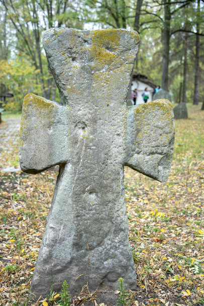 Ένα φθαρμένο σημάδι τάφου από ψαμμίτη στη σκιά μια πολύ φωτεινή μέρα. Δεν υπάρχει κανένα κείμενο ορατό στην πέτρα, αλλά υπάρχουν κάποια βρύα στην κορυφή. Επιτύμβια στήλη και τάφοι σε αρχαίο νεκροταφείο εκκλησίας. - Φωτογραφία, εικόνα