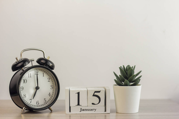 January 15 on a wooden calendar, next to a retro alarm clock and a succulent in a mini pot on a light table.One day in January.Winter day.A copy of the space.Workplace. - Foto, imagen