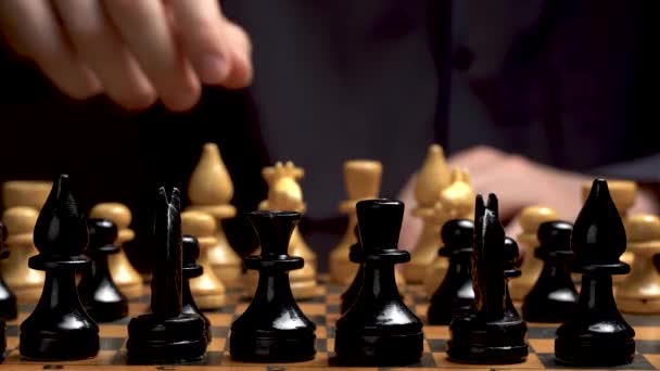 Bordspel schaken. De speler snijdt stukken in schaken. Sport Strategie en gokken. de speler is een man aan een tafel in een donkere sleutel. Een man in een shirt aan een goktafel. - Video