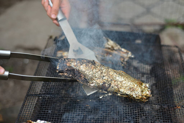 Kucharz zamienia pieczoną rybę w siatkę metalową łopatką.. - Zdjęcie, obraz