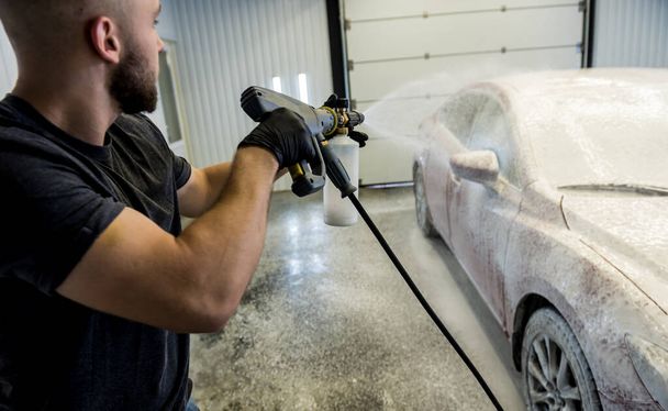 Worker washing car with active foam on a car wash. - Фото, зображення