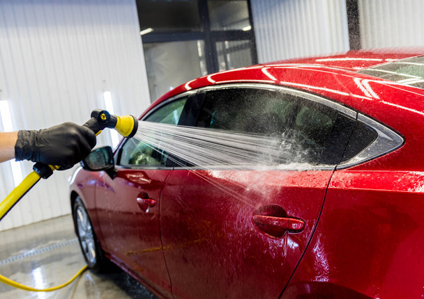 Service worker washing car on a car wash. - Foto, Imagem