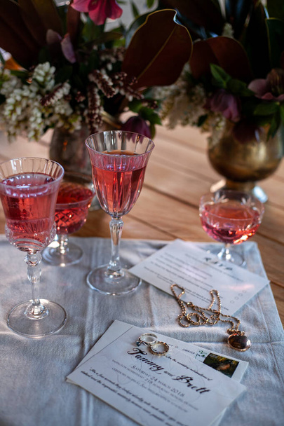 crystal glasses with rose wine, flowers on a wooden table. Wedding decoration - Foto, imagen