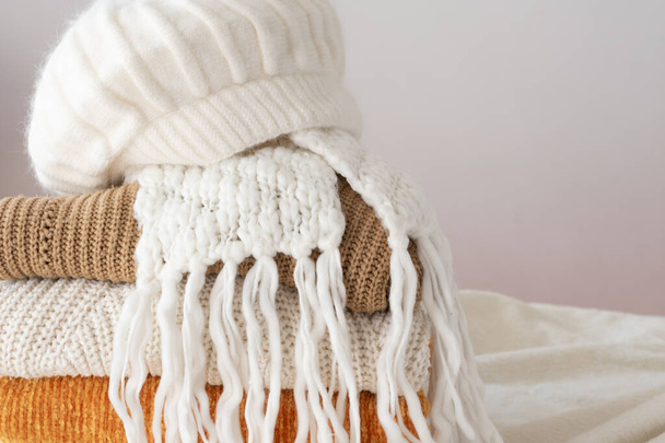 Lots of winter clothes, wool sweaters of different colors, a scarf and a hat - Photo, Image