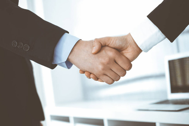 Businessman and woman shaking hands in office. Concept of handshake as success symbol in business - Foto, Imagem