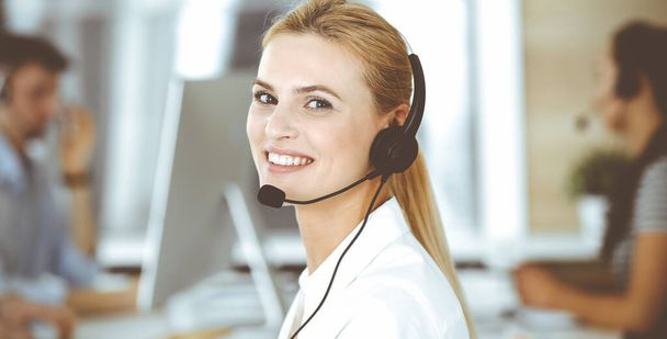Blonde business woman using headset for communication and consulting people at customer service office. Call center. Group of operators at work - Φωτογραφία, εικόνα