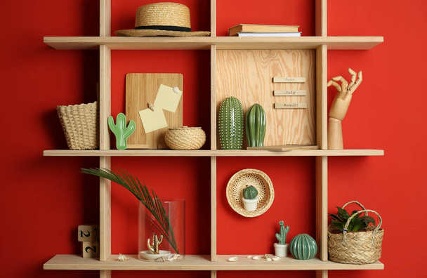 Stylish wooden shelves with decorative elements on red wall - Valokuva, kuva
