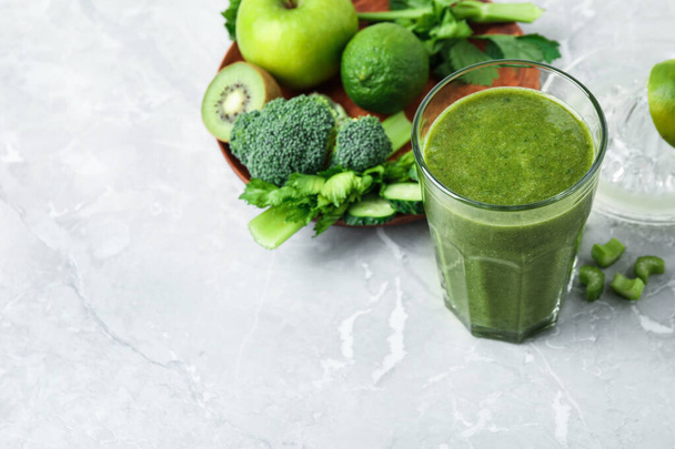 Delicious green juice and fresh ingredients on grey marble table, space for text - Foto, Bild
