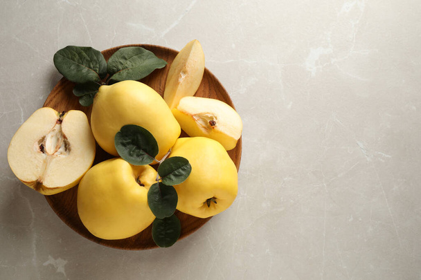 Fresh ripe organic quinces with leaves on light table, top view. Space for text - Valokuva, kuva