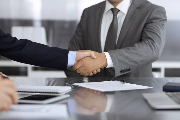 Unknown business people are shaking hands after contract signing in modern office, close-up. Handshake as successful negotiation ending - 写真・画像
