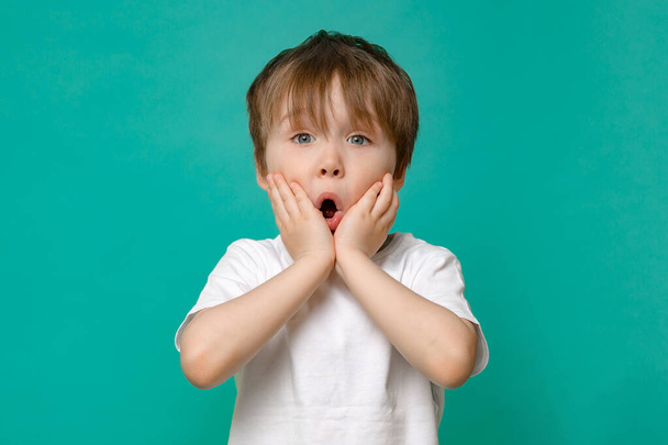 hermoso niño de cinco años de edad en una camiseta blanca muestra gestos de la mano y emociones en un aislado Copiar el espacio de fondo - Foto, Imagen
