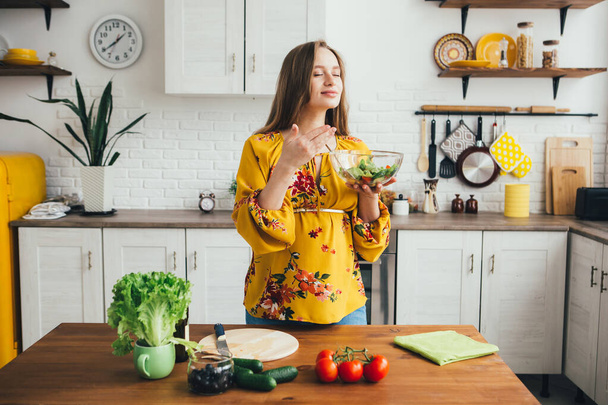 Young cute pregnant girl preparing vegetable salad in the kitchen. The concept of healthy eating. Toning. - Foto, afbeelding