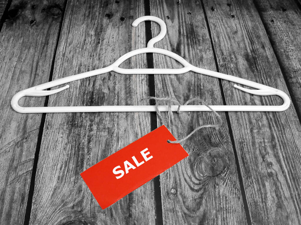 coat hanger and blank red price tag on wooden background, clothing sales, closeup - Photo, Image