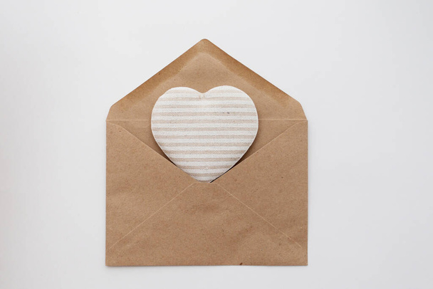 Coeur tissulaire dans une enveloppe artisanale. Saint Valentin respectueux de l'environnement - Photo, image