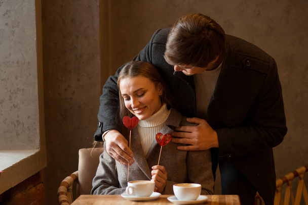 Nuori pari istuu kahvilassa kahvin ja tikkarisydämen kanssa. Ystävänpäivä. - Valokuva, kuva